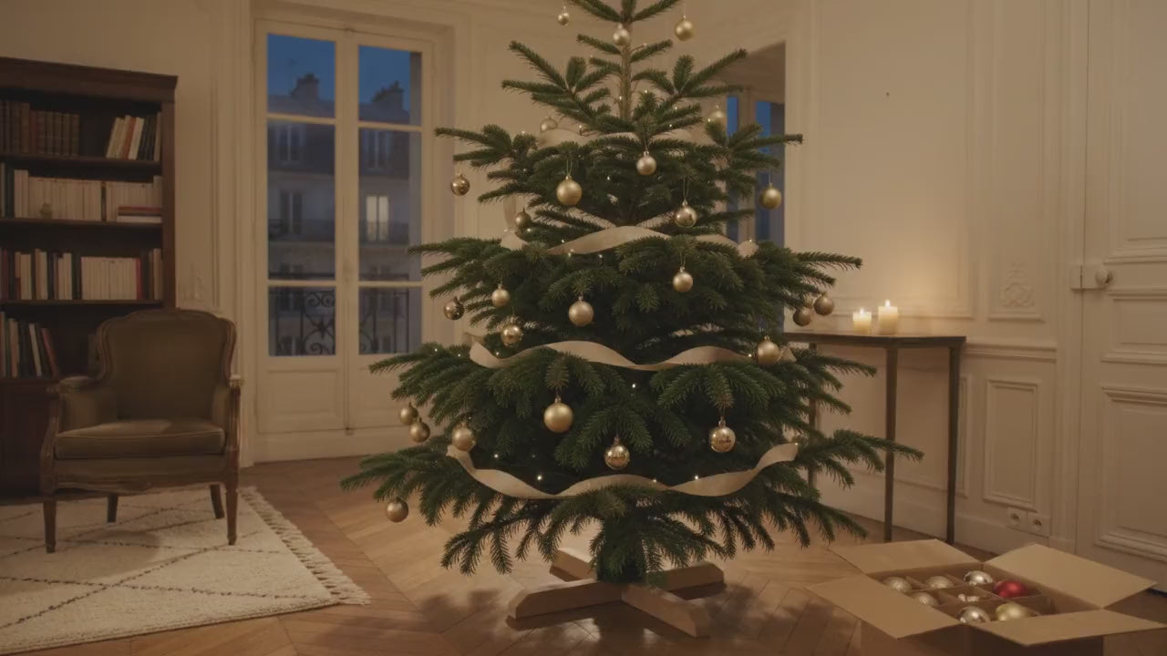 Sapin de Noël artificiel vert réaliste décoré de boules dorées dans un salon parisien